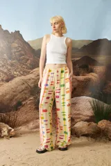 Pantalón de corte ancho con diseño gráfico multicolor sobre fondo beige, confeccionado con impresión digital.