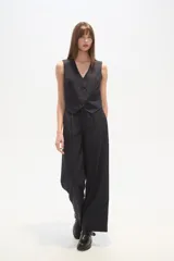 Chaleco de vestir sin mangas, color negro con finas rayas verticales blancas. Presenta escote en V, cierre frontal con botones y bolsillos falsos a la altura de la cintura.