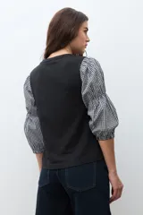 Remera de cuello redondo en color negro con mangas tres cuartos abullonadas que presentan un estampado de cuadros Vichy en blanco y negro.