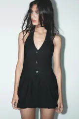 Minivestido negro con forma de chaleco, cuello halter, escote en pico, botones metálicos y bajo globo.
