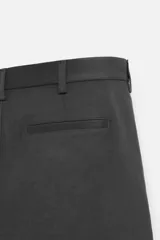 Pantalón chino negro slim fit confeccionado en tejido técnico de secado rápido. Cuenta con bolsillos frontales y traseros de vivo. Cierre frontal con cremallera y botón.
