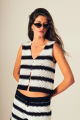 Top tejido a crochet con rayas horizontales blancas y negras, escote en V y cierre frontal con botones.