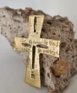 Colgante con forma de cruz de bronce con detalles grabados.