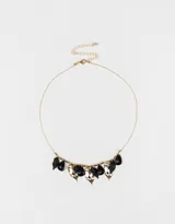 Collar corto dorado con cadena de eslabones y extensión, con dijes colgantes de resina negra y metal dorado.
