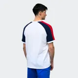 Remera de algodón blanca con mangas cortas ranglan azul marino con una franja roja en el hombro. Tiene el logo de Umbro bordado en el pecho y el escudo del Club Nacional de Football.