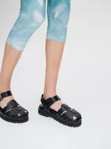 Sandalias romanas color verde oliva, con tiras entrecruzadas y hebilla lateral. Suela de goma negra con plataforma de 3cm. Fabricadas en cuero vacuno.