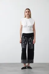 Top sin mangas color beige, confeccionado en tejido acanalado. Presenta hombreras definidas y un recorte fruncido bajo el busto que ajusta la silueta.