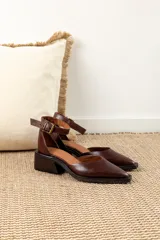 Zapato de cuero color marrón chocolate con punta cuadrada, corte lateral y pulsera al tobillo con hebilla dorada.