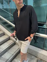 Camisola negra de lino con cuello mao y mangas largas con puños abotonados. Cierre frontal con botones de madera.