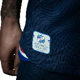 Camiseta de fútbol Umbro del Club Nacional de Football, modelo Away 2 temporada 2025, para hombre. Diseño azul con detalles en blanco y rojo en cuello y mangas. Incluye logo de Umbro, escudo del club y sponsor Antel en el frente. Presenta un patrón de ondas en relieve en el tejido.