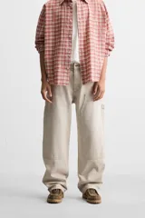 Pantalón color marrón con efecto lavado, corte relaxed fit, cinco bolsillos, aplicación de tira y bolsillo multifunción en perneras, cierre frontal con cremallera y botón.