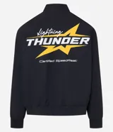 Campera negra con cuello alto, cierre de botones y estampado estilo racing con logos y textos en amarillo, rojo y blanco. Tiene bolsillos laterales y mangas largas con detalles estampados. Marca Blue Steel.