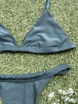 Conjunto de bikini verde oscuro, con corpiño triangular fijo y bombacha colaless regulable. Incluye abertura para agregar tazas soft.