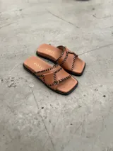 Sandalias color suela de cuero con tiras cruzadas y pespuntes negros.