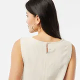 Blusa corta color crema de lino sin mangas y cuello redondo.
