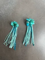 Par de aros colgantes con piedras turquesas y flecos de hilo y cuentas azules.