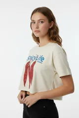 Remera corta color crema con estampado de pimientos y texto en azul. De corte holgado y cuello redondo.