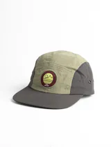 Gorro con visera de cinco paneles, combinado en color verde oliva y gris. Presenta un parche circular con logo bordado en el frente.