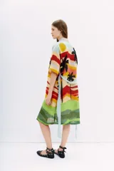Kimono largo de lino con estampado de paisaje playero con palmeras, en tonos celeste, amarillo, rojo, verde y negro. Tiene mangas amplias, bolsillos al frente y lazo en la cintura.