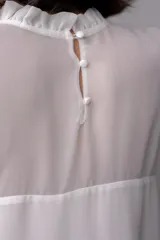 Blusa blanca de gasa con volados en el frente y mangas acampanadas.