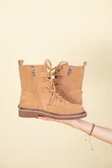 Bota de cuero gamuzado, con cordones, doble hebilla en la parte superior y cierre lateral interno.