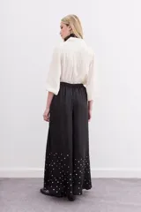 Pantalón amplio de viscosa color negro, con caída fluida, cintura elastizada y lentejuelas en la botamanga.