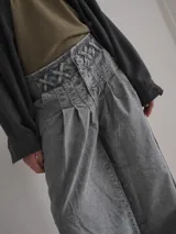 Pantalón vaquero de corte ancho, color crudo, con cintura alta y detalle de costuras cruzadas en la parte superior.