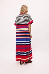 Vestido de tejido de punto color blanco y negro a rayas horizontales, con detalles en rojo y azul en el ruedo y cuello. Presenta cuello redondo con borde rojo y costuras decorativas azules.