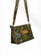Bandolera de cuero verde con estampado animal print dorado y correa de cuero trenzada.