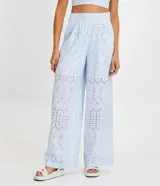 Pantalón largo de tela laise color celeste con textura de florcitas y calados. Tiene corte ancho, bolsillos laterales y cierre invisible.