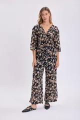 Pantalón de corte palazzo con estampado floral en tonos beige sobre fondo negro.