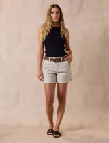 Short de jean azul oscuro con pretina con pasadores, botón y cierre. Delantera con bolsillos. Botón en bolsillos traseros. Incluye cinturón trenzado marrón con hebilla redonda dorada.