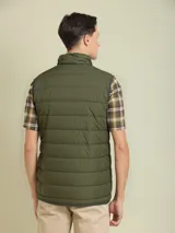 Chaleco negro acolchado con cuello alto y cierre frontal con cremallera.