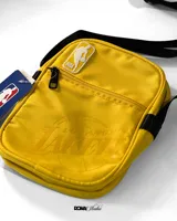 Bandolera amarilla con logo de la NBA y llavero con el logo de Los Angeles Lakers.