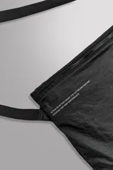 Bandolera negra de tejido técnico con correa ajustable, cierre con cremallera y detalle de texto y logo estampados.