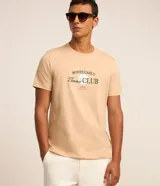 Remera color arena de algodón, con cuello redondo y mangas cortas. Estampa frontal con el texto "Monte Carlo Tennis Club" en color verde.