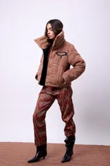 Campera corta con estampado abstracto en tonos marrones y beige, cuello alto, cierre frontal con botones a presión, bolsillos delanteros y bordado negro con las iniciales CP. Forro interior y relleno liviano de guata.