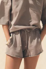 Shorts de tiro alto confeccionados en tejido con efecto lavado, cintura elástica ajustable con cordones, bolsillos laterales de vivo y tejido combinado en rib a tono.