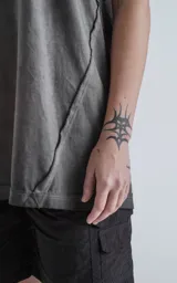 Remera gris con cuello redondo y sisas amplias, con recortes en delantero y mangas y efecto gastado.