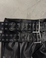 Shorts negros de efecto cuero con doble cinturón incorporado, con múltiples hebillas cuadradas plateadas y ojales metálicos.