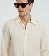 Camisa celeste de lino con cuello camisero, abotonadura frontal y mangas largas.