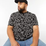 Camiseta negra de manga corta con cuello redondo y estampado de figuras de Keith Haring en color blanco.