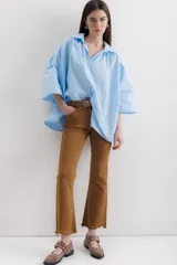 Camisa celeste de algodón con corte amplio, cuello camisero y mangas largas con puños abullonados.