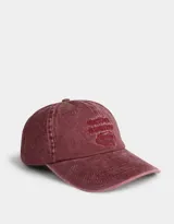 Gorra de béisbol color borgoña, confeccionada en denim con efecto lavado. Presenta bordado frontal con texto y regulador metálico trasero.