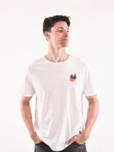 Remera blanca de corte recto con estampado pequeño de palmeras y sol en el pecho.