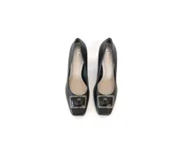 Zapato de cuero negro con punta cuadrada, aplique metálico en el empeine y taco ancho de altura media con textura geométrica.