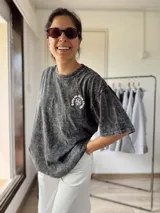 Remera gris con efecto lavado y estampado de trébol con texto en el frente. Corte holgado y mangas cortas.