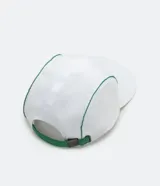 Gorra blanca de cinco paneles con visera plana y ribetes verdes. Presenta un estampado con un pez koi, texto en japonés y la palabra "Tokyo" en verde.