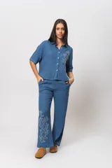 Conjunto de camisa y pantalón de tela simil lino color celeste con bordado de cactus en color blanco. La camisa es de manga corta y el pantalón es de corte palazzo.
