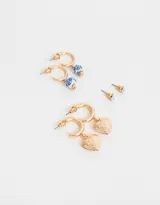 Set de tres pares de aros dorados: un par de aros tipo argolla con dije de corazón labrado, un par de aros tipo argolla con dije de cerámica estampada en azul y blanco, y un par de aros tipo botón con perlas sintéticas.
